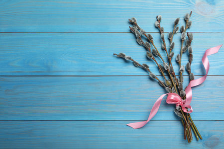 Beautiful bouquet of pussy willow branches on light blue wooden background, top view. Space for textの写真素材
