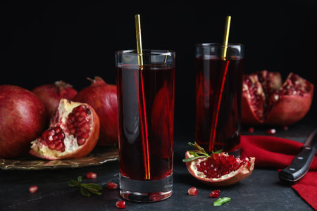 Pomegranate juice and fresh fruits on black tableの写真素材