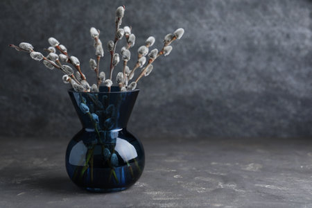 Beautiful bouquet of pussy willow branches in vase on gray table. Space for textの写真素材