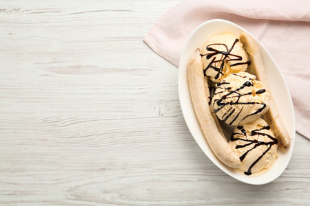 Delicious banana split ice cream with chocolate topping on white wooden table, top view. Space for textの写真素材