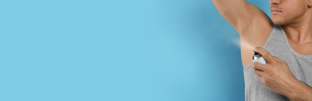 Man applying deodorant to armpit on turquoise background, closeup. Space for text