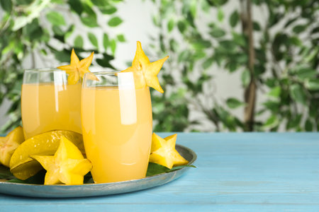 Delicious carambola juice in glasses on light blue wooden table. Space for textの写真素材