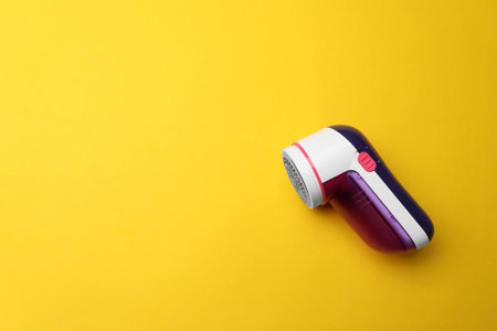 Modern fabric shaver on yellow background, top view. Space for textの写真素材