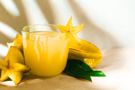 Delicious carambola juice in glass on light tableの写真素材