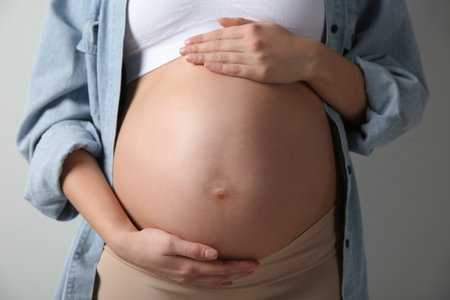 Pregnant woman touching her belly on light gray background, closeupの写真素材