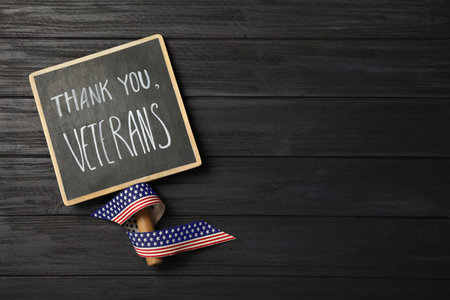 Sign with phrase Thank You, Veterans and ribbon on black wooden table, top view. Space for textの写真素材