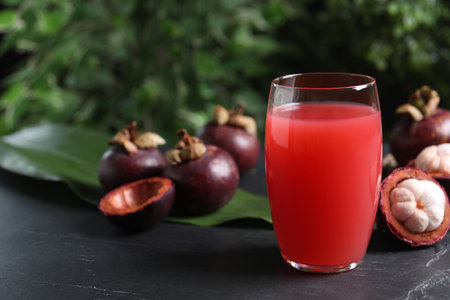Delicious mangosteen juice in glass on dark table, space for textの写真素材