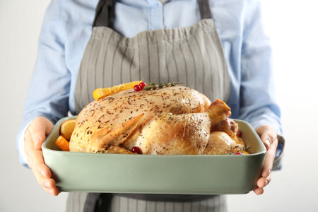 Woman holding raw chicken with orange slices on light gray background, closeupの写真素材