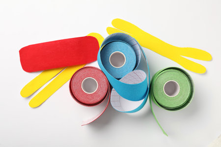 Bright kinesiology tape rolls and pieces on white background, flat layの写真素材