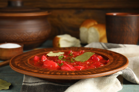 Stylish brown clay plate with Ukrainian borsch served on wooden tableの写真素材