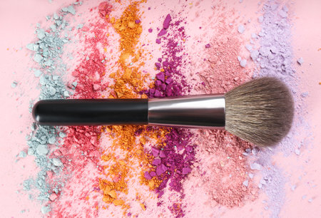 Makeup brush and scattered eye shadows on pink background, flat layの写真素材