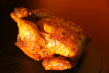 Delicious grilled whole chicken on black tableの写真素材