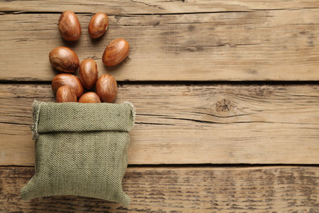 Overturned sackcloth bag with jackfruit seeds on wooden table, flat lay. Space for textの写真素材