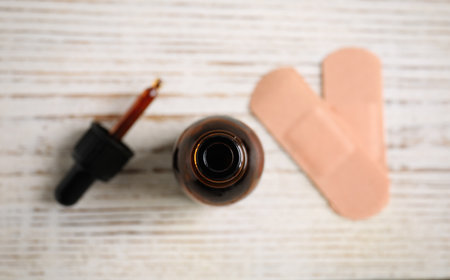 Bottle of medical iodine, dropper and sticking plasters on white wooden table, flat layの写真素材