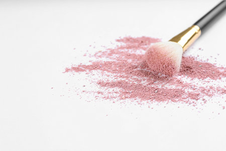 Makeup brush with crushed cosmetic product on light background. Space for textの写真素材