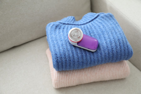 Modern fabric shaver and woolen sweaters on sofa indoorsの写真素材
