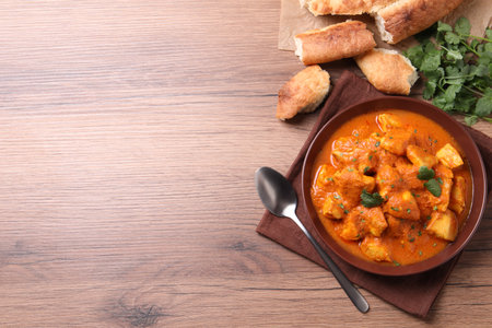 Bowl of delicious chicken curry on wooden table, flat lay. Space for textの写真素材