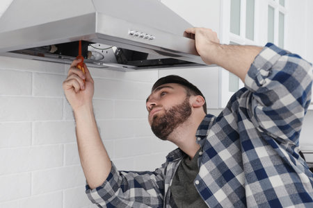 Man repairing modern cooker hood in kitchenの写真素材