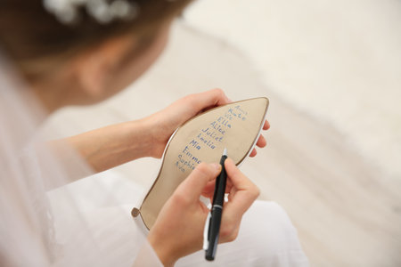 Young bride writing her single friends names on shoe indoors, above view. wedding superstitionの写真素材
