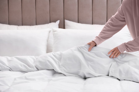 Woman making bed with stylish lines in room, closeupの写真素材