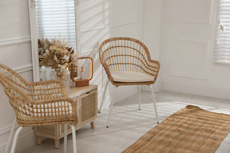 Living room interior with wooden commode, mirror and wicker chairsの写真素材