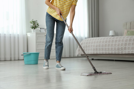 Woman cleaning floor with mop at home, closeup