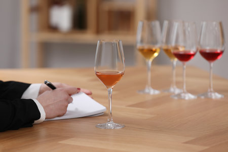 Sommelier making notes during wine tasting at table indoors, closeupの写真素材