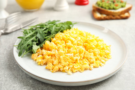 Tasty scrambled eggs with arugula served for breakfast on gray tableの写真素材