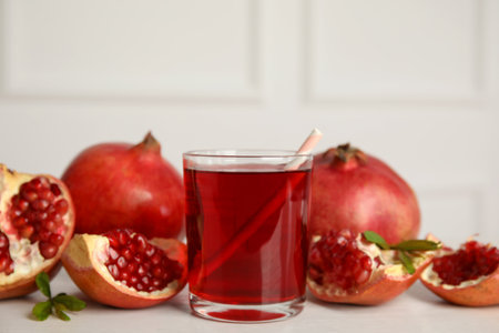 Glass of pomegranate juice and fresh fruits on white tableの写真素材