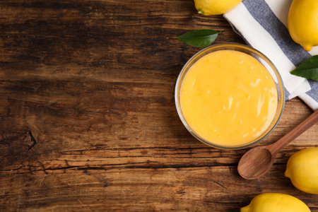 Delicious lemon curd and fresh fruits on wooden table, flat lay. Space for textの写真素材