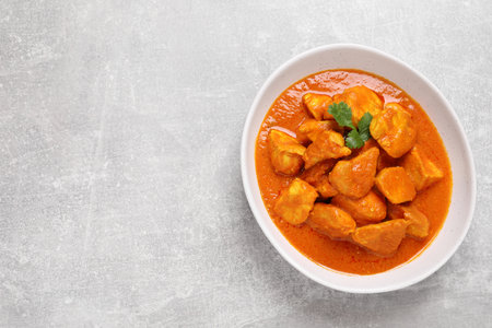 Bowl of delicious chicken curry on light gray table, top view. Space for textの写真素材