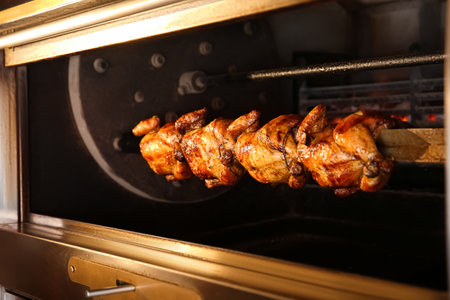 Grilling whole chickens in rotisserie machine, closeupの写真素材