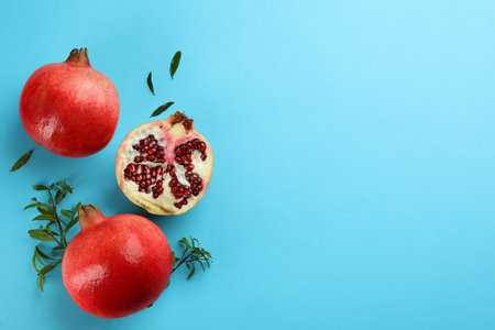 Flat lay composition with ripe pomegranates on light blue background. Space for textの写真素材
