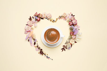 Beautiful heart shaped floral composition with cup of coffee on beige background, flat layの写真素材