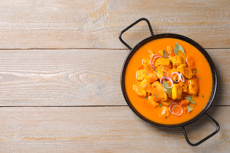Delicious chicken curry in pan on wooden table, top view. Space for textの写真素材