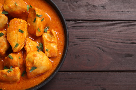 Delicious chicken curry in pan on wooden table, top view. Space for textの写真素材