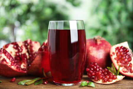 Pomegranate juice in glass and fresh fruits on wooden table outdoorsの写真素材