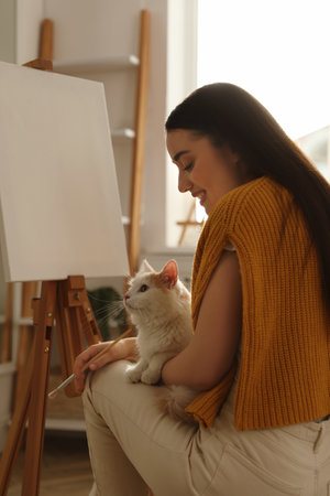 Beautiful young woman with drawing brush and cat at homeの写真素材