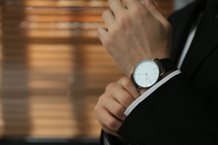 Businessman with luxury wrist watch indoors, closeup. Space for textの写真素材