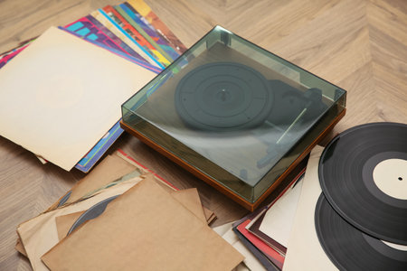 Stylish turntable with vinyl records on floorの写真素材