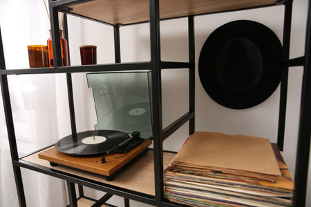 Stylish turntable with vinyl record on shelving unit indoorsの写真素材