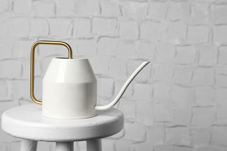 Ceramic watering can on table against white brick wall, space for textの写真素材