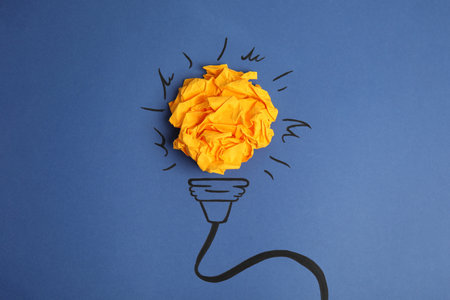 Composition with crumpled paper ball and drawing of lamp bulb on blue background, top view. creative...