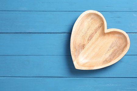 Empty heart shaped wooden plate on blue table, top view. Space for textの写真素材