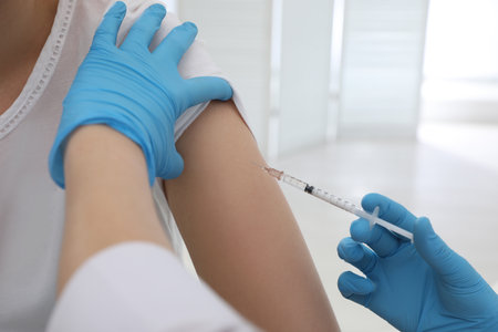 Doctor giving injection to woman in hospital, closeup. Immunization conceptの写真素材