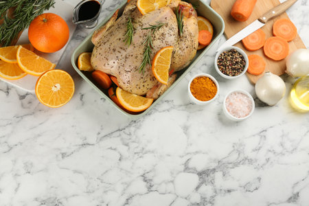 Raw chicken, orange slices and other ingredients on white marble table, flat lay. Space for textの写真素材