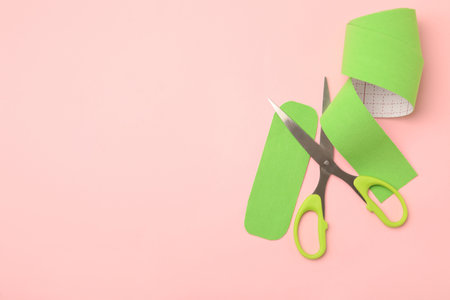 Bright kinesiology tape pieces and scissors on pink background, flat lay. Space for textの写真素材
