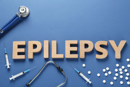 Word Epilepsy made of wooden letters, stethoscope, pills and syringes on blue background, flat layの写真素材