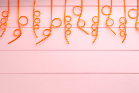 Orange plastic drinking straws on pink wooden table, flat lay. Space for textの写真素材
