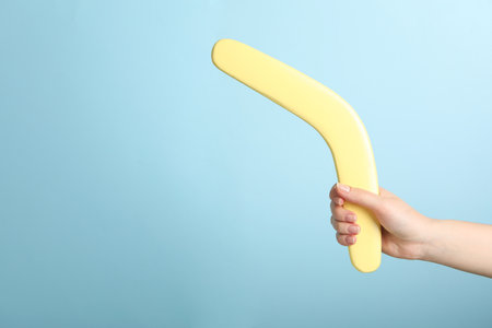 Woman holding boomerang on light blue background, closeup. Space for textの写真素材